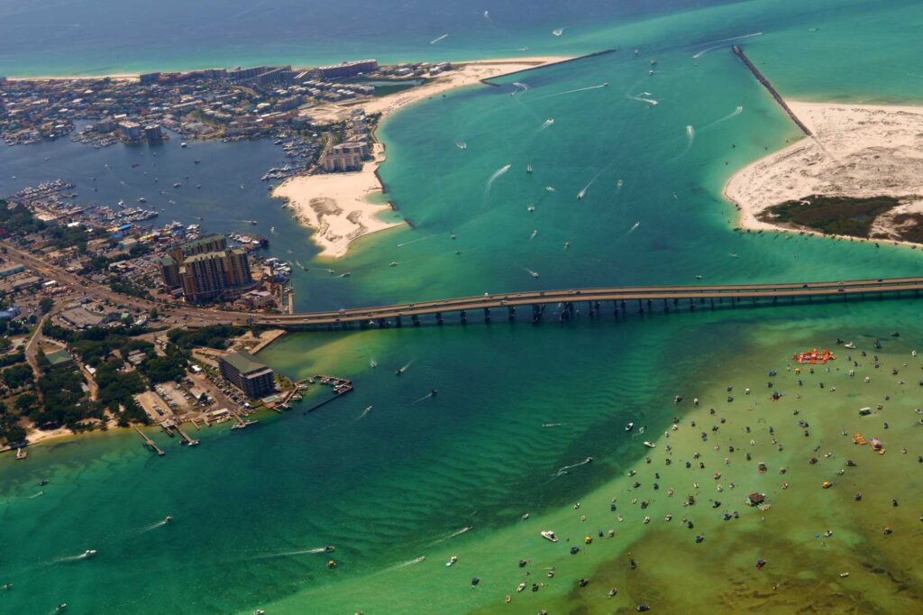 Aerial image of the Destin Harbor in Destin, FL, showing the East Pass, Crab Island, and the Marler Bridge.